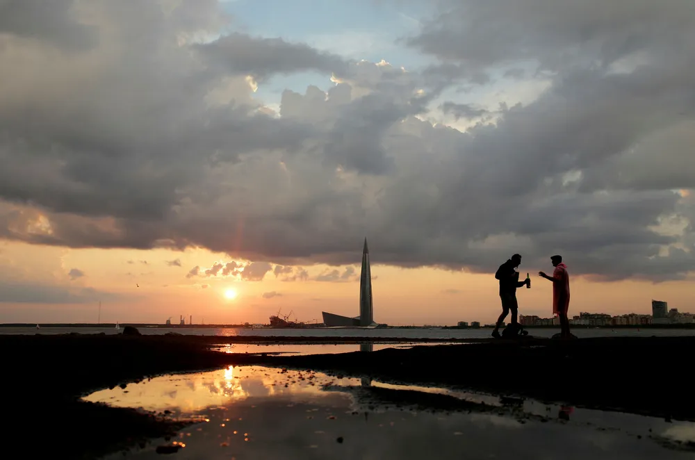 Dark time ahead: people enjoy sunset on a Baltic shore in St Petersburg in Russia, with Gazprom's headquarters - Lakhta Centre - seen in the background