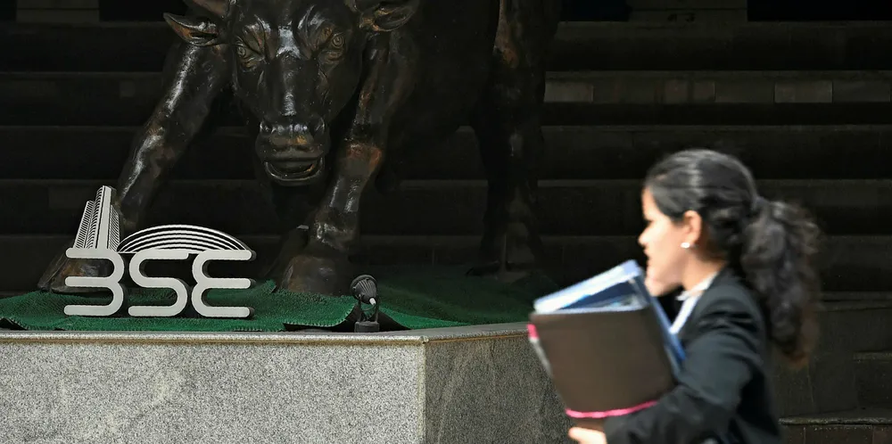 An Indian woman speaks on her phone while walking past a Bull sculpture outside the Bombay Stock Exchange (BSE) in Mumbai.
