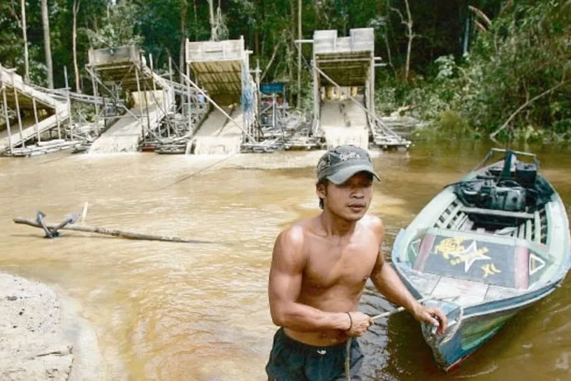 Wading in: a traditional gold miner tows a boat at a mine on the Takaras river in Kalimantan province