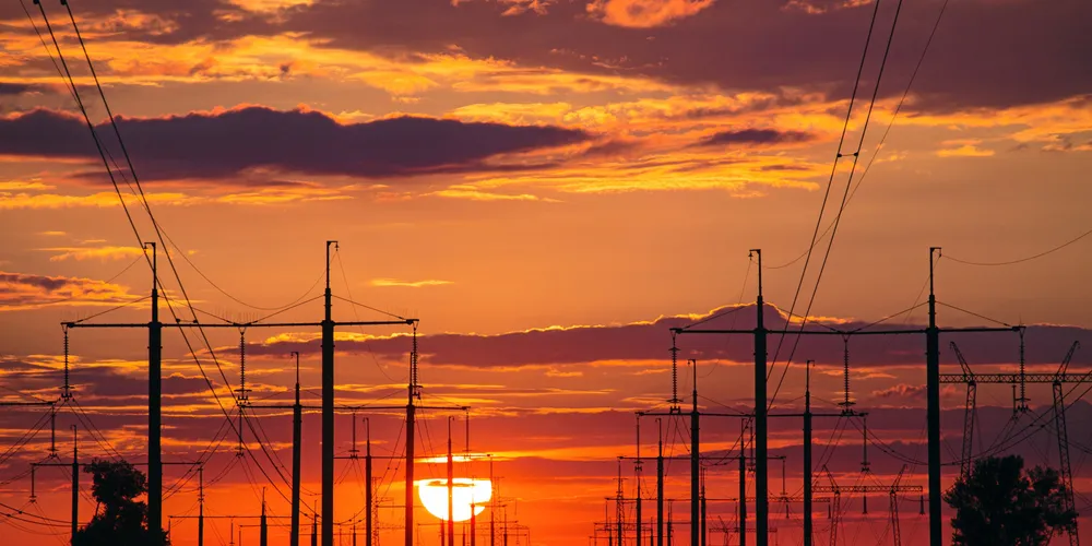 Sunset above high voltage power lines and electricity pylons on the fie