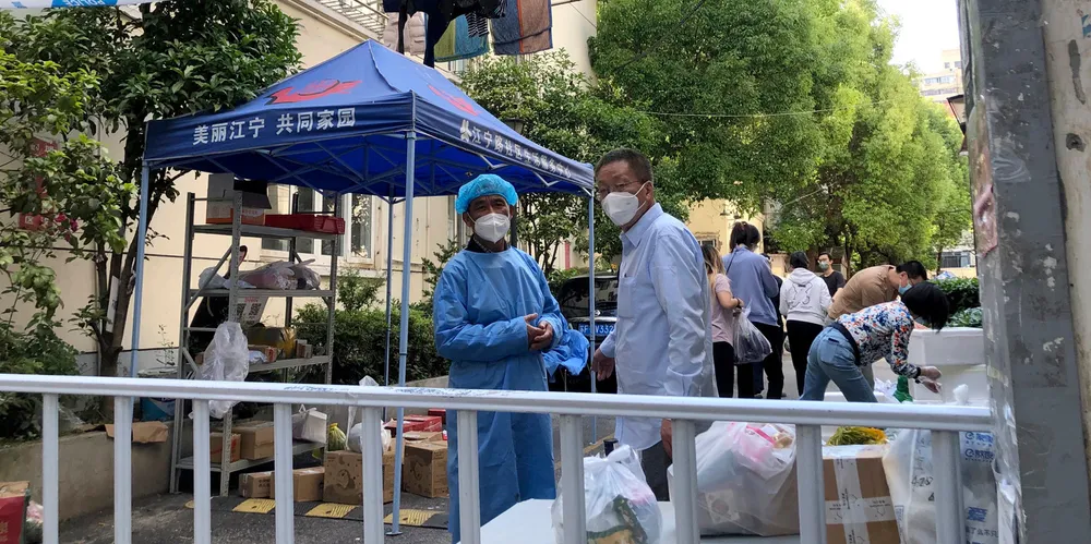 Workers wearing face masks stand near a parcel pickup area in a neighbourhood in Shanghai, China, on in May. More than 26m people in Shanghai were confined for two months in one of the country’s strictest and most visible lockdowns.