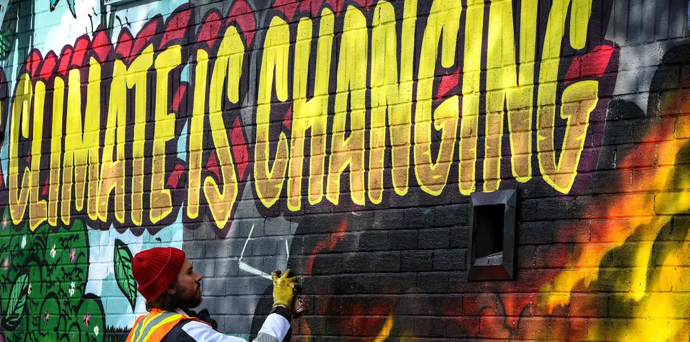 A street artist paints a mural on a wall opposite the COP26 climate summit venue in Glasgow.