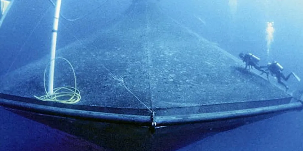 Divers clean the outside of SeaStation 3000, an open-ocean aquaculture project operated by the University of Hawaii.
