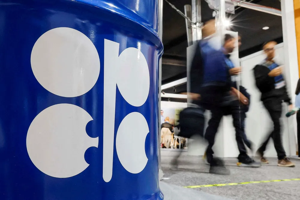 People walk past a barrel of oil with the Opec logo.