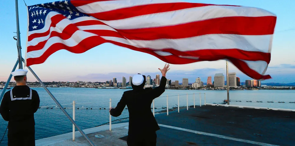 Sailors lower the US flag aboard the aircraft carrier USS Ronald Reagan at the naval base in Coronado, California