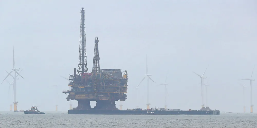 Shell's Brent Delta oil platform is towed past offshore wind turbines en route to Able Seaton Port for decommissioning