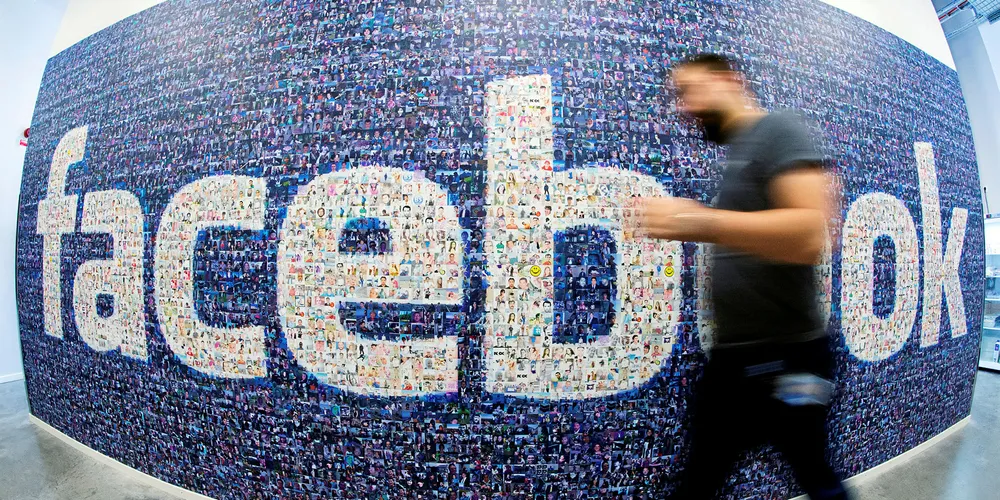 Man walks past a big logo created from pictures of Facebook in Sweden