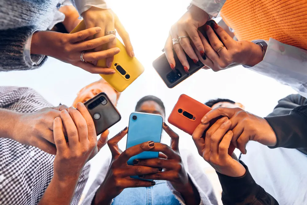 Teens in circle holding smart mobile phones – Multicultural young people using cellphones outside – Teenagers addicted to new technology concept ---