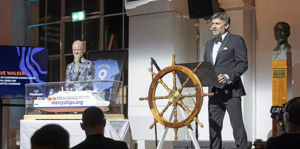 (At the wheel) David Walker, the Geneva Cargo Day Committee chairman and head of chartering at Sahara Group, and (behind ship model) Bryce Wagner, executive director of Mercy Ships.