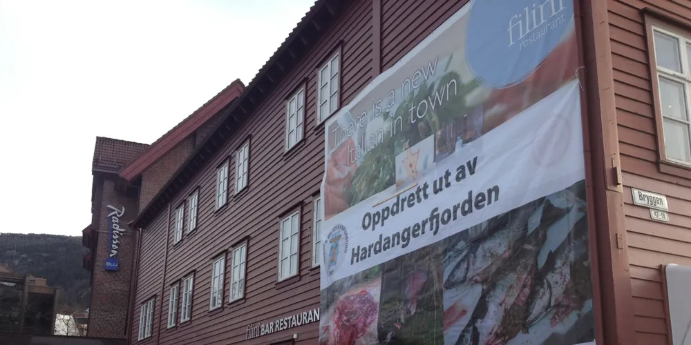 Fem aktivistar frå NMF hengte opp eit stort banner på husveggen til SAS Hotell Norge på Bryggen i Bergen.