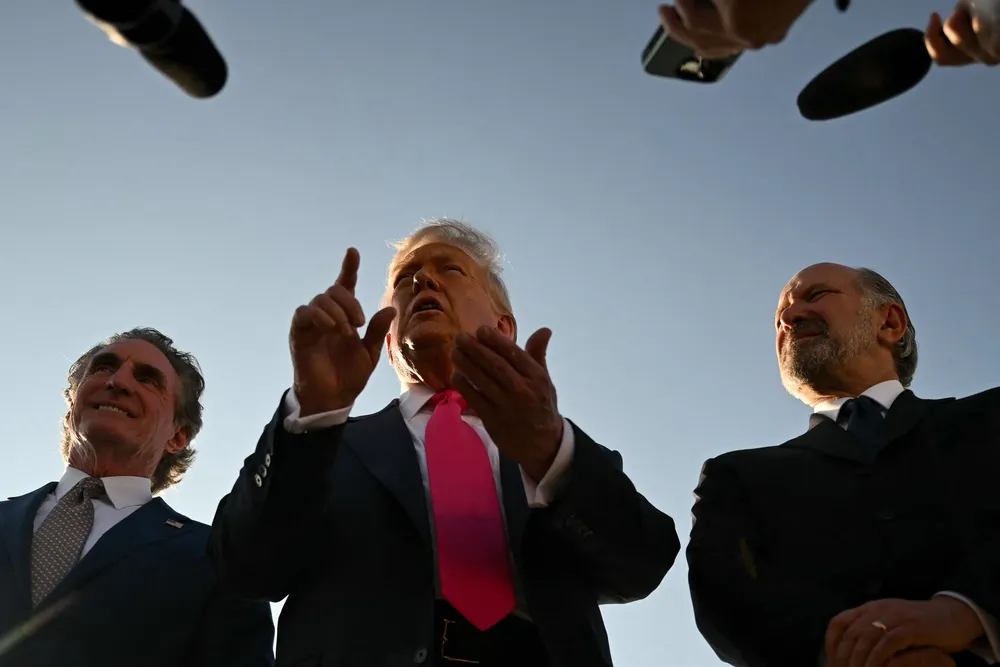 US President Donald Trump (centre), flanked by US Secretary of the Interior Doug Burgum (left) and US Secretary of Commerce Howard Lutnick (right), speaks to reporters after stepping off Air Force One upon arrival at Joint Base Andrews, Maryland on 15 July 2025.
