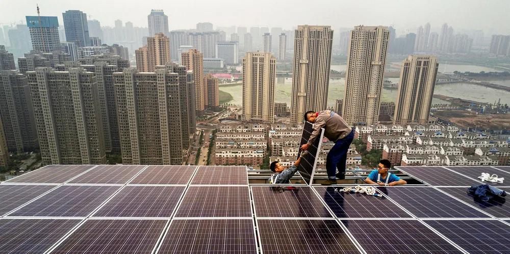 Chinese workers from Wuhan Guangsheng Photovoltaic Company work on a solar panel project on the roof of a 47 story building in a new development.