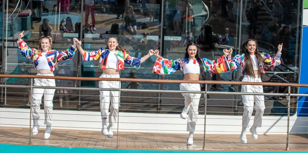 Performers on a Royal Caribbean cruise ship celebrate the announcement of Eurovision-themed cruises.