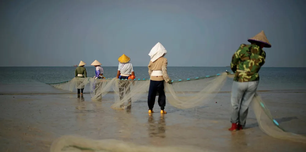Fishermen collect their net as they fish on Silver beach in Beihai, in southwestern China's Guangxi province. The area wants to unite offshore wind and aquaculture.