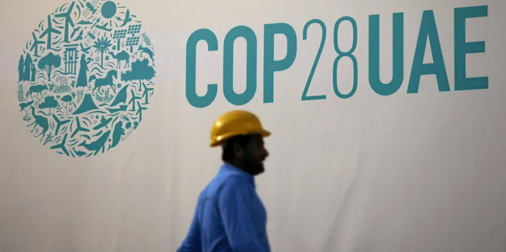 A construction worker passes an event sign ahead of the COP28 climate conference in Dubai.