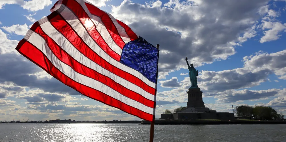 An American flag flies on the back of a boat in front of the Statue of Liberty on May 12, 2021 in New York City.