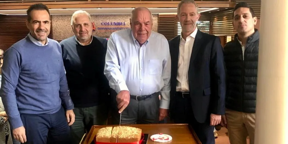 Columbia Shipmanagement founder Heinrich Schoeller cuts the company’s 2023 new year’s cake, alongside chief executive Mark O’Neil (second from right).