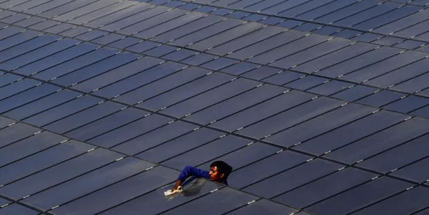 A worker cleans panels at a PV array near Gandhinagar, north of Ahmedabad