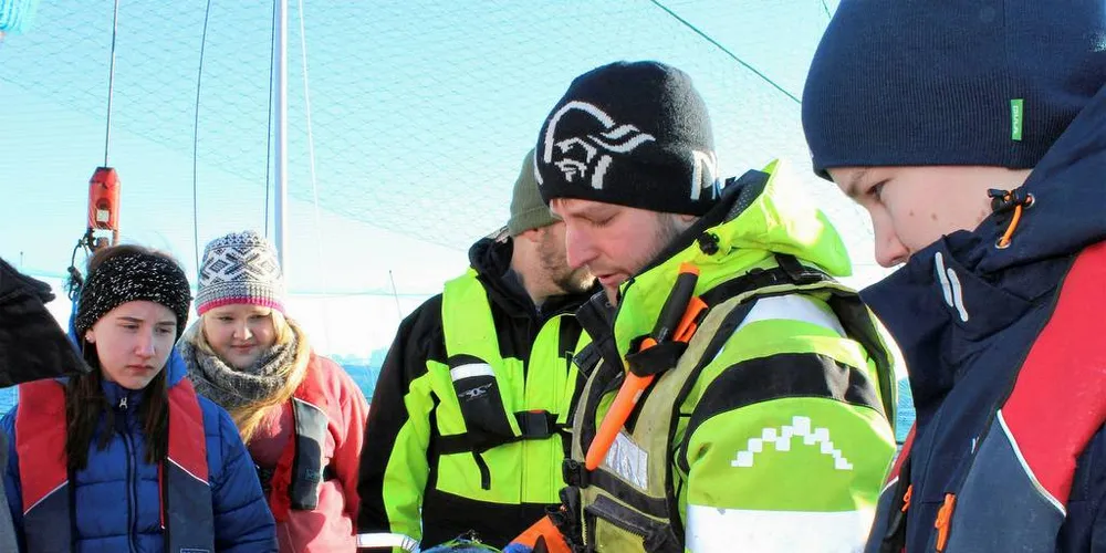 Ungdom på laksebesøk. Ungdomsskoleelevene Helle Hilstad, Marte Hansen og Steinar Engseth fra Øresvik skole i Rødøy følger interessert med mens Håvard Olsen i Kvarøy fiskeoppdrett studerer og forklarer.Foto: Kenneth Didriksen