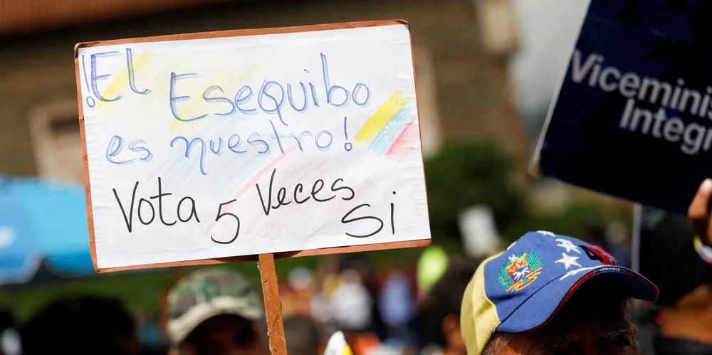 A Venezuelan government supporter holds a sign that reads: ‘The Essequibo is ours, vote YES 5 times.’