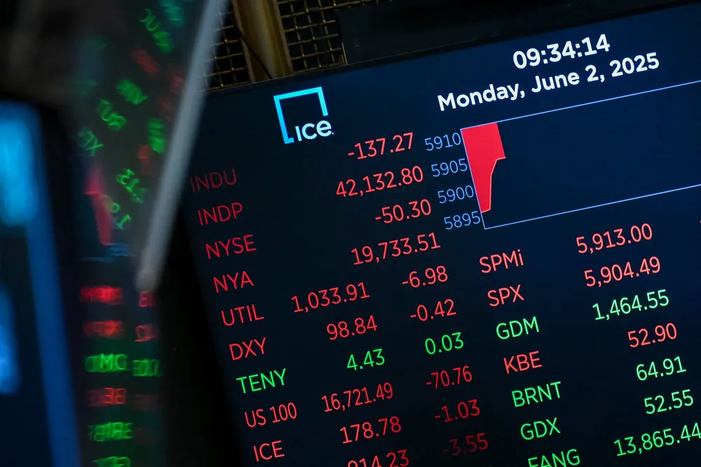 Market statistics are displayed on a screen as traders work on the floor of the New York Stock Exchange.