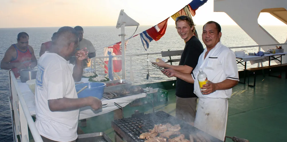 Seafarers enjoy a barbecue on the deck of a container ship. Social events are helping improve morale on board.