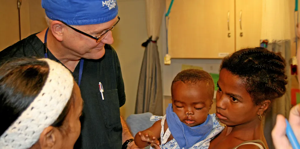 Surgeon Dr Gary Parker, who has been with Mercy Ships since 1986, talks to patients during his morning rounds on the Africa Mercy hospital ship