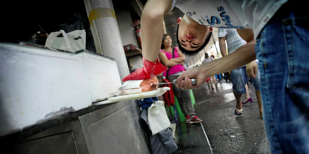 Chinese fish market worker Fan Jian cuts a salmon fillet in Shanghai.