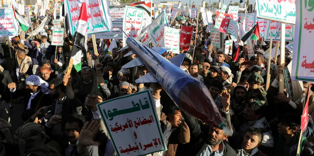 People supporting the Houthis hold a mock-up rocket.