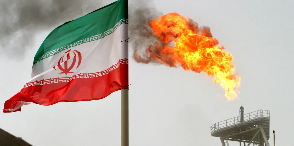 A gas flare on an oil production platform is seen alongside an Iranian flag in the Gulf.