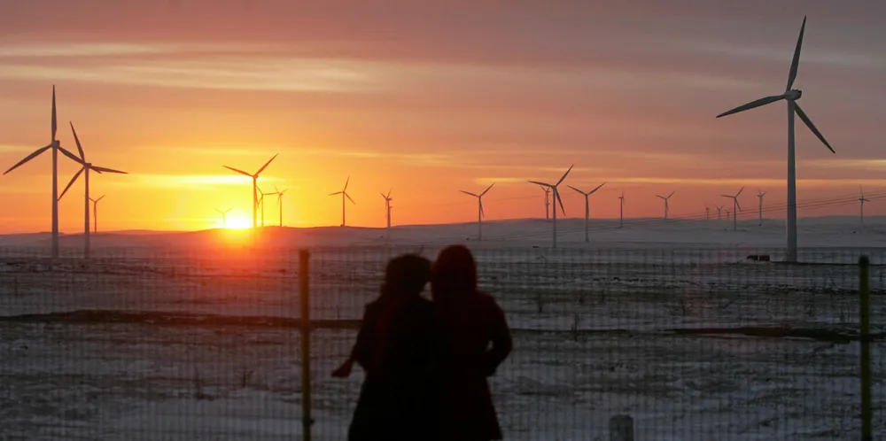 Two tourists view the Huitengxile Wind Farm at sunset January 28, 2007 in Wulanchabu League of Inner Mongolia Autonomous Region, China.