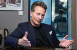 Runar Vatne er investor og eiendomsinvestor. Bak han henger avisutklipp og et bilde av han som liten i olabil.